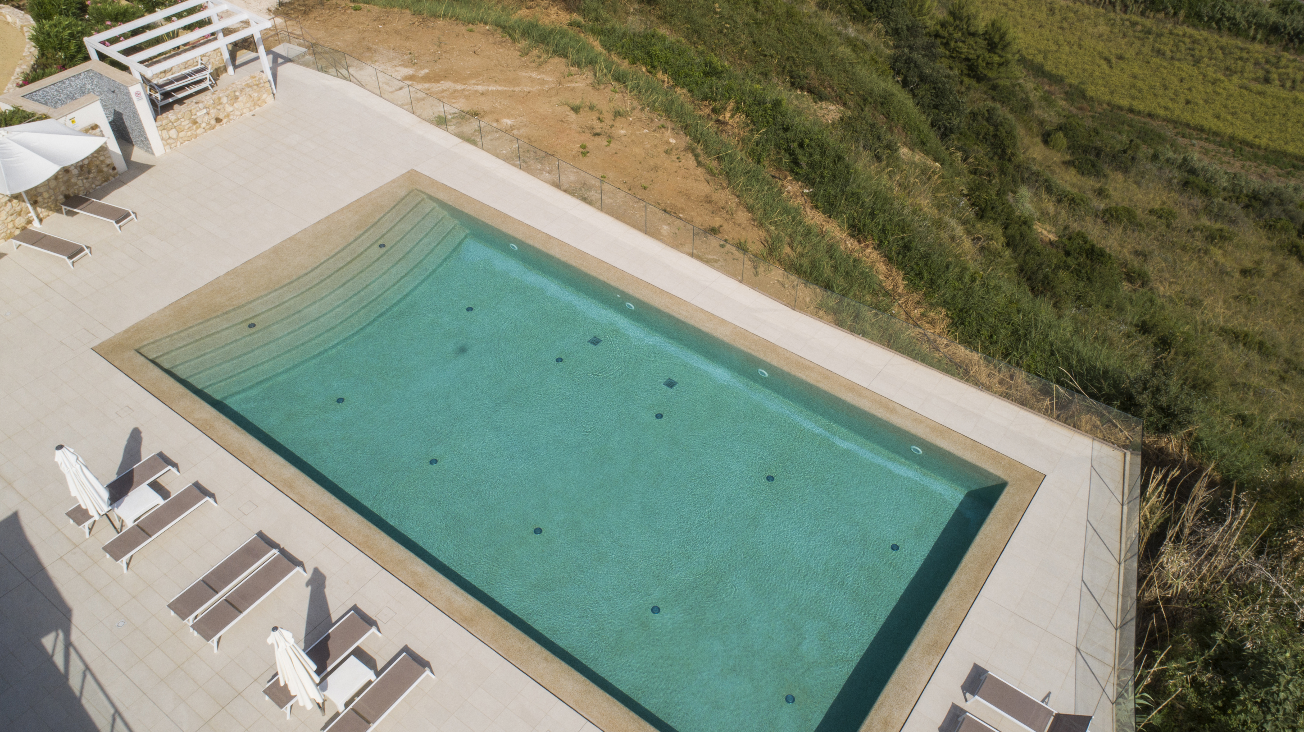 Piscina interrata Classic con sfioro totale a fessura e scalinata di ingresso - Realizzata da Piscine Design